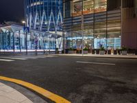 a street that has cars on it and people standing outside at a bus stop in the night