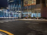 a street that has cars on it and people standing outside at a bus stop in the night