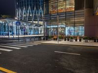 a street that has cars on it and people standing outside at a bus stop in the night