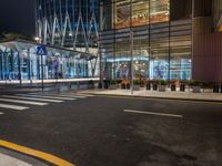 a street that has cars on it and people standing outside at a bus stop in the night