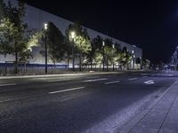 empty street lit up at night by street lamps and concrete pavement by curbed roadway