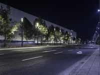 empty street lit up at night by street lamps and concrete pavement by curbed roadway