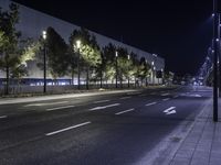 empty street lit up at night by street lamps and concrete pavement by curbed roadway