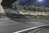 a empty street at night under the lights of the buildings, near an overpass