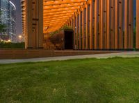 a view of the back of a wooden building with stairs leading to it and a grass area with benches