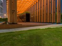 a view of the back of a wooden building with stairs leading to it and a grass area with benches