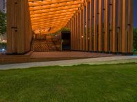 a view of the back of a wooden building with stairs leading to it and a grass area with benches