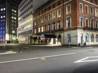 a deserted city street with a fire hydrant and tall buildings behind it at night