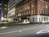 a deserted city street with a fire hydrant and tall buildings behind it at night