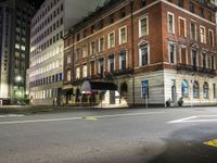 a deserted city street with a fire hydrant and tall buildings behind it at night