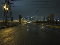 a night street is lit with lights and wires on poles for the power lines to go over