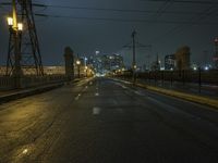 a night street is lit with lights and wires on poles for the power lines to go over