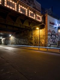 a street scene with the illuminated traffic light below and a graffiti covered tunnel over it