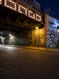 a street scene with the illuminated traffic light below and a graffiti covered tunnel over it