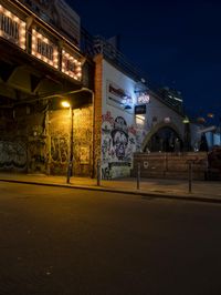 a street scene with the illuminated traffic light below and a graffiti covered tunnel over it
