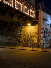 a street scene with the illuminated traffic light below and a graffiti covered tunnel over it