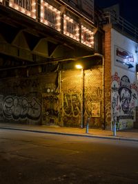 a street scene with the illuminated traffic light below and a graffiti covered tunnel over it