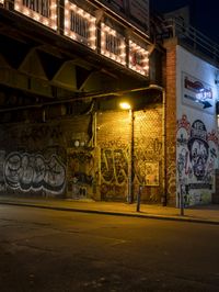 a street scene with the illuminated traffic light below and a graffiti covered tunnel over it