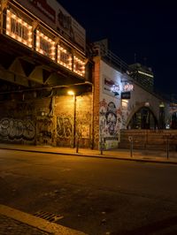 a street scene with the illuminated traffic light below and a graffiti covered tunnel over it