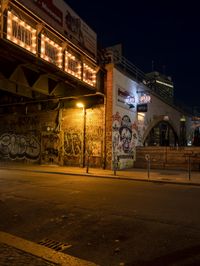 a street scene with the illuminated traffic light below and a graffiti covered tunnel over it