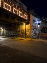 a street scene with the illuminated traffic light below and a graffiti covered tunnel over it