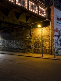 a street scene with the illuminated traffic light below and a graffiti covered tunnel over it
