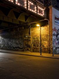 a street scene with the illuminated traffic light below and a graffiti covered tunnel over it