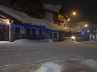 a snow covered street near some houses and lights in the air with one person walking under it