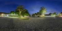 a street at night with cars parked on the side of it and lights in the trees