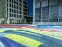 the view of the street with colorful carpet at night in the city park with modern buildings and a large window