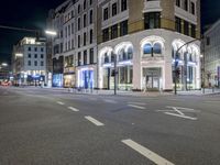 a street is empty of people or cars at night time and is lit up with lights