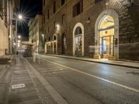 a night shot showing the streets in an old european city with buildings and people walking by