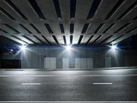 empty street under an overpass at night with multiple lights above it in an urban city setting