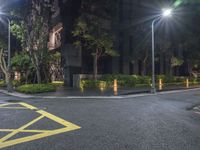 a corner with a parking lot at night with parking lights on and a street in front