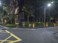 a corner with a parking lot at night with parking lights on and a street in front