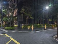 a corner with a parking lot at night with parking lights on and a street in front