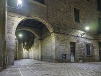 street lights shine brightly along an empty cobblestone courtyard and stone steps leading to two buildings