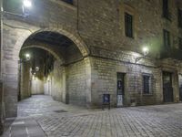 street lights shine brightly along an empty cobblestone courtyard and stone steps leading to two buildings