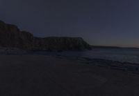 a bench that is in front of some rocks and water at sunset with the moon and trees