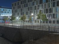 many tall buildings are visible at night near a road and waterbanks on the city's south bank