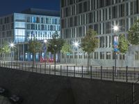 many tall buildings are visible at night near a road and waterbanks on the city's south bank