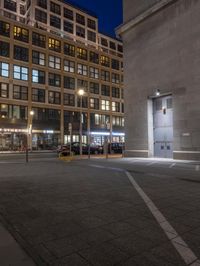 the two buildings are very near one another at night, and the street lights shine behind them
