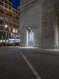 the two buildings are very near one another at night, and the street lights shine behind them