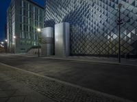 a photo of a person walking down a street at night in front of a building that has a glass fence around the side