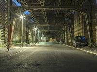 a car is driving underneath the steel bridge on an empty street at night time,