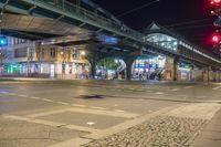 a street with some people crossing over the bridge at night time and several cars on the roadway below