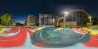 a ball painted on a painted surface in front of a large building at night time