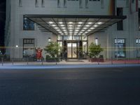 a hotel with two men outside the entrance at night time, and a storefront door