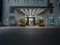 a hotel with two men outside the entrance at night time, and a storefront door