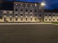 a building lit up with lights at night time in the street, with an empty road